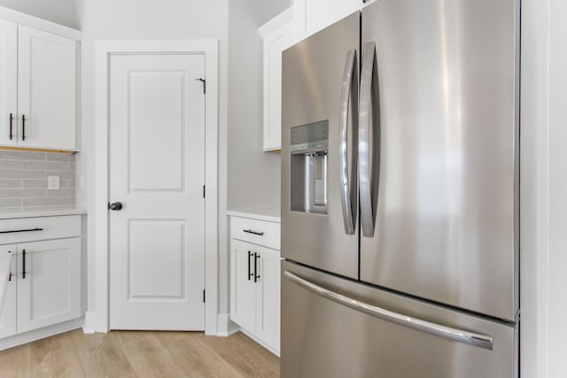 kitchen with decorative backsplash, light hardwood / wood-style flooring, white cabinets, and stainless steel fridge with ice dispenser