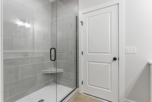 bathroom featuring a shower with shower door and wood-type flooring