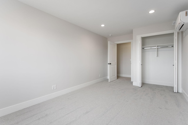 unfurnished bedroom with light colored carpet, a closet, and a wall unit AC