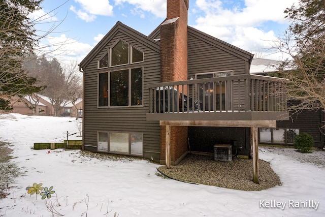 snow covered house featuring a wooden deck and central AC unit