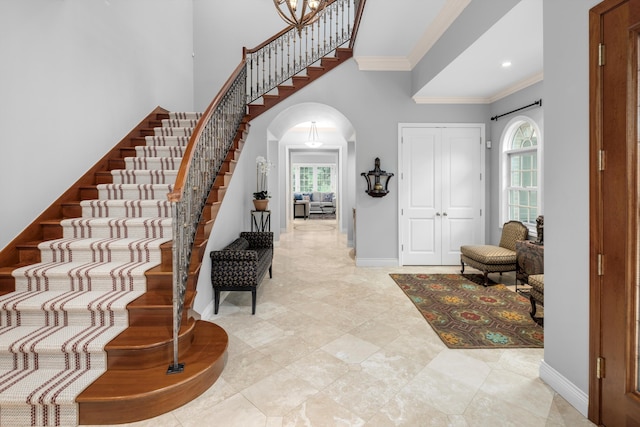 foyer entrance with crown molding, a healthy amount of sunlight, and a towering ceiling