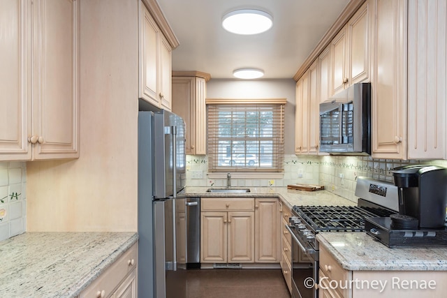 kitchen with light brown cabinets, light stone counters, tasteful backsplash, a sink, and stainless steel appliances