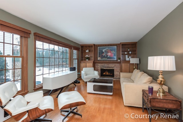 living room with light wood finished floors, a fireplace, and built in shelves