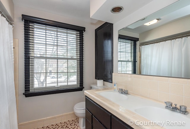 full bath with backsplash, toilet, baseboards, and a sink