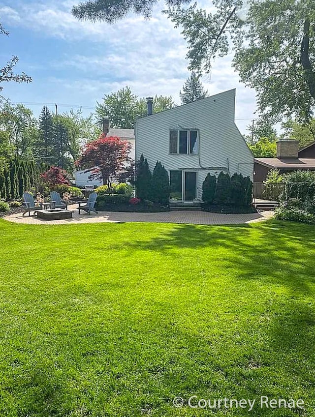 back of property with a patio, a lawn, and an outdoor fire pit