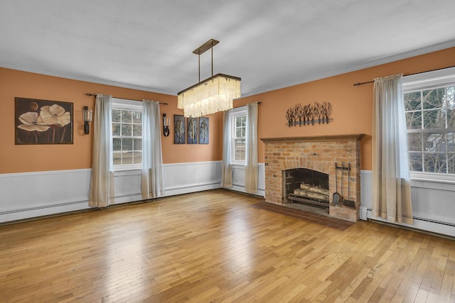 unfurnished living room featuring crown molding, a fireplace, light hardwood / wood-style flooring, and a wealth of natural light