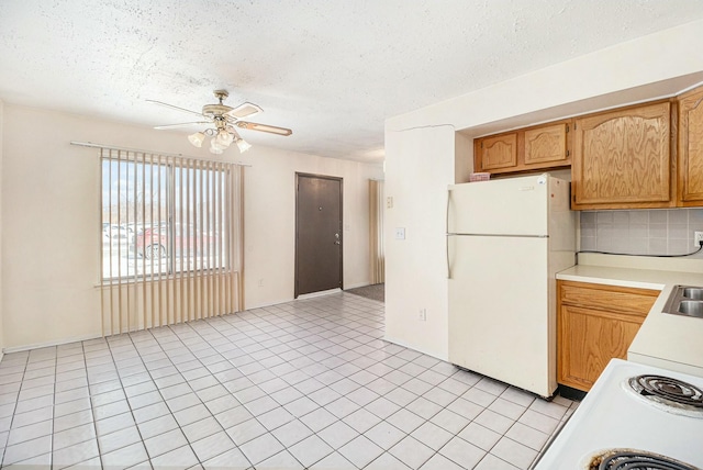 kitchen with white refrigerator, light tile patterned flooring, ceiling fan, and decorative backsplash