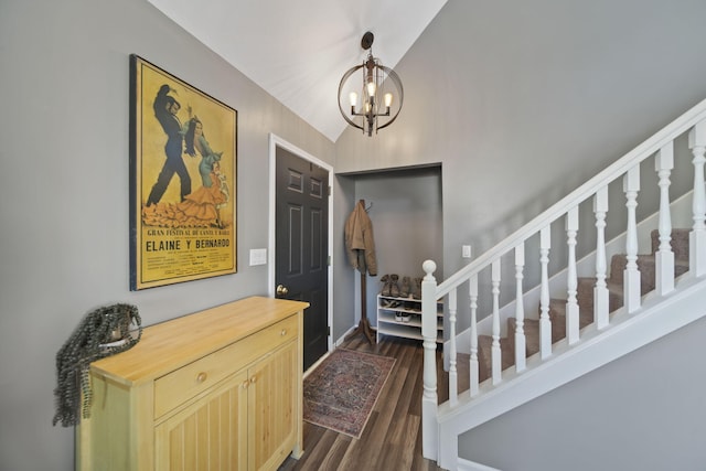 entryway with dark wood finished floors, vaulted ceiling, stairway, and an inviting chandelier