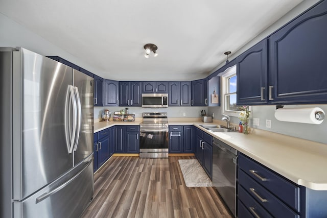 kitchen with stainless steel appliances, dark wood-type flooring, a sink, light countertops, and blue cabinetry