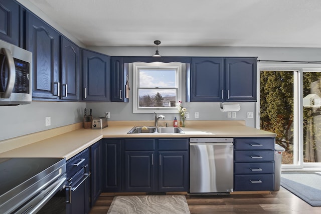 kitchen with blue cabinets, appliances with stainless steel finishes, light countertops, and a sink