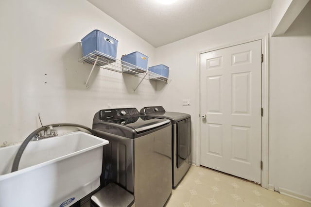 washroom featuring laundry area, washer and dryer, light floors, and a sink