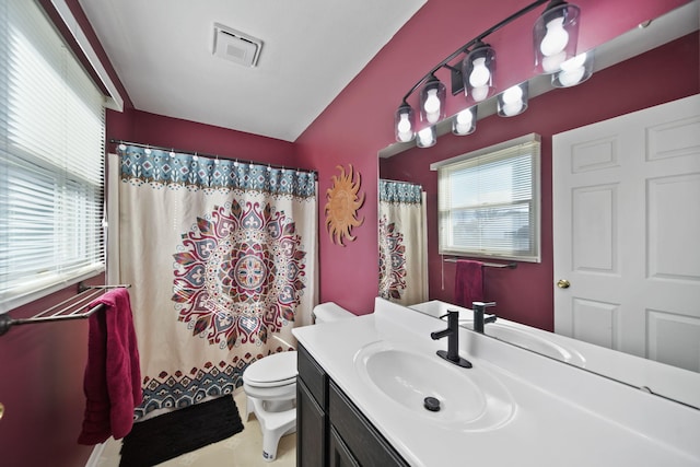 bathroom featuring toilet, vanity, visible vents, and a healthy amount of sunlight