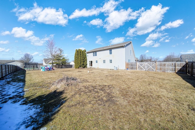 back of house featuring a gate, a fenced backyard, and a lawn