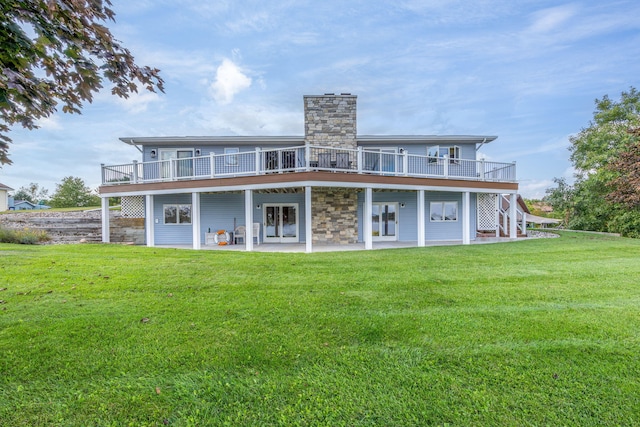 rear view of property featuring a deck, a patio, and a lawn