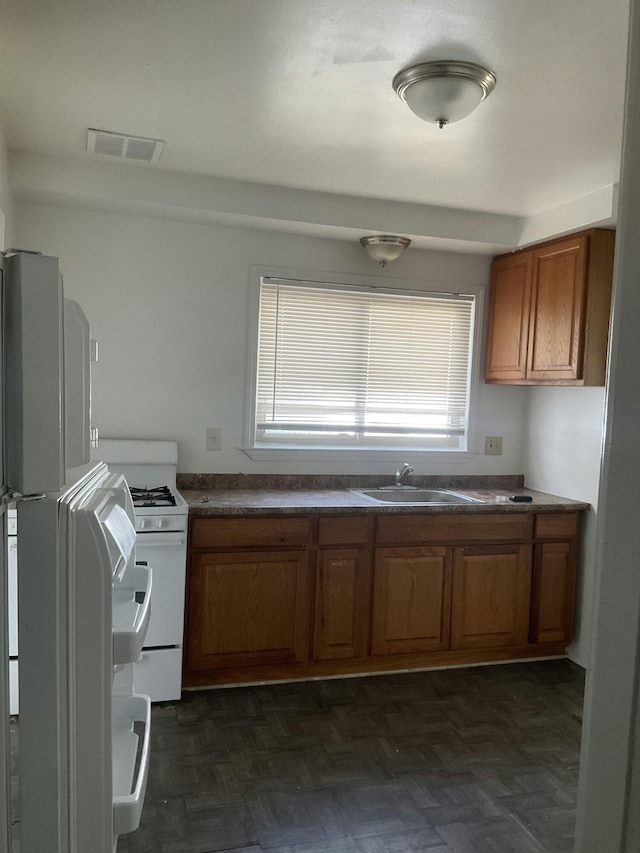 kitchen featuring dark parquet flooring, sink, and white appliances