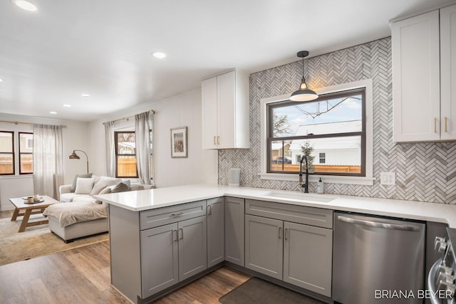 kitchen featuring sink, gray cabinetry, decorative light fixtures, stainless steel dishwasher, and kitchen peninsula