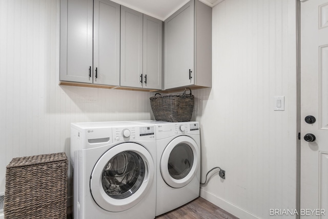 clothes washing area with washer and dryer, cabinets, and wood-type flooring