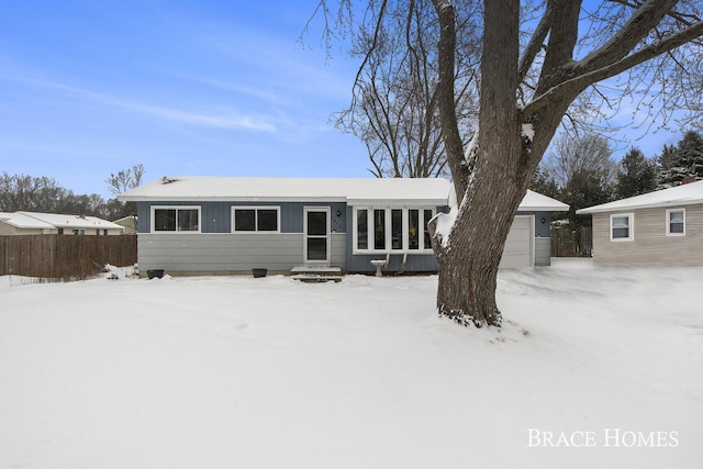 snow covered back of property featuring a garage