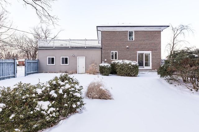 snow covered house featuring entry steps and fence