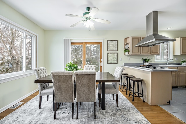 dining area with baseboards, wood finished floors, visible vents, and a healthy amount of sunlight