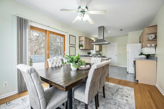 dining area featuring light wood finished floors, a ceiling fan, and baseboards