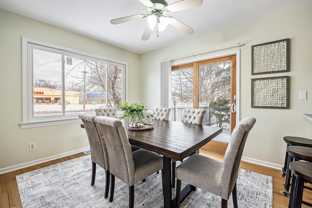 dining space with a ceiling fan, baseboards, and wood finished floors