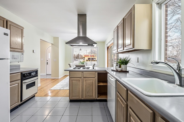 kitchen featuring light tile patterned floors, light countertops, a sink, island range hood, and white appliances