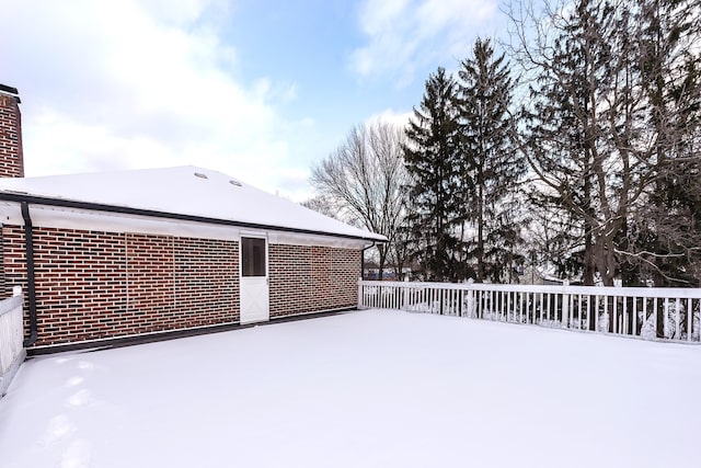 snow covered house featuring brick siding