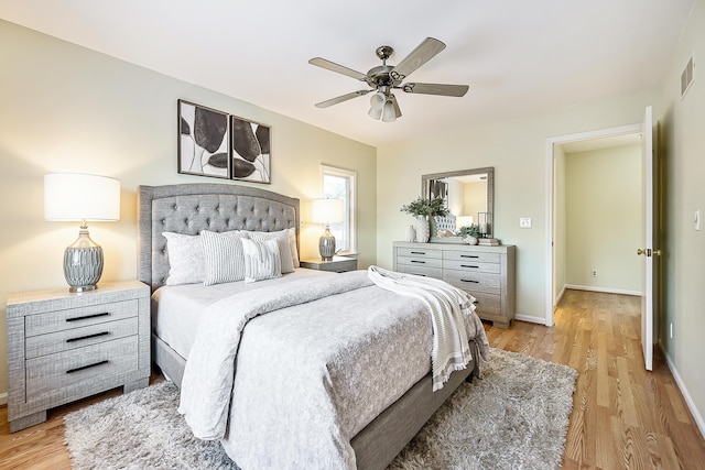 bedroom featuring light wood finished floors, ceiling fan, visible vents, and baseboards