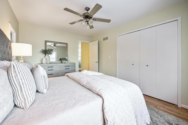 bedroom featuring ceiling fan, a closet, visible vents, and wood finished floors