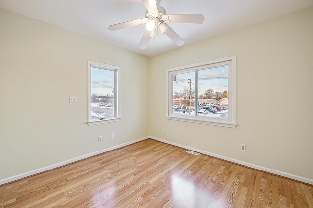 unfurnished room with light wood finished floors, baseboards, visible vents, and ceiling fan