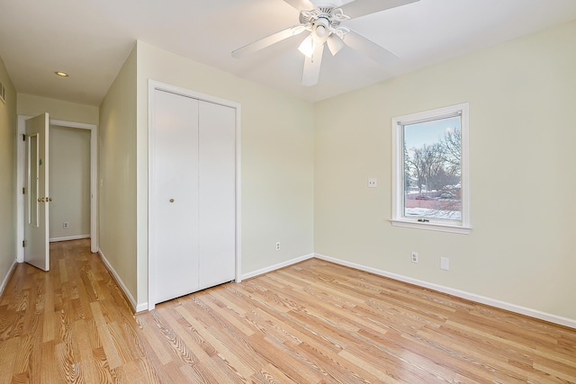 unfurnished bedroom with a closet, ceiling fan, light wood-style flooring, and baseboards