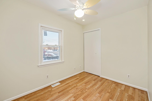 empty room with baseboards, visible vents, ceiling fan, and light wood finished floors