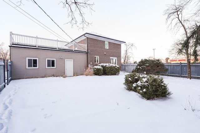 snow covered back of property with a fenced backyard