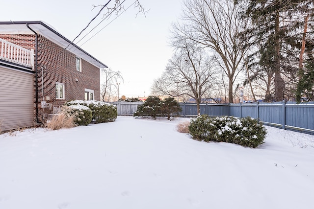 snowy yard with a fenced backyard