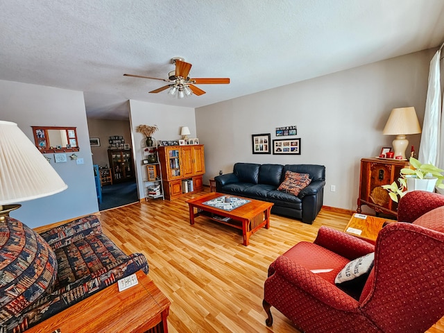 living room featuring ceiling fan, wood-type flooring, and a textured ceiling