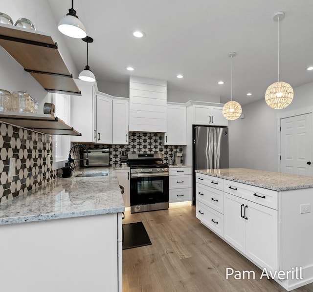 kitchen featuring sink, white cabinetry, hanging light fixtures, light hardwood / wood-style flooring, and stainless steel appliances