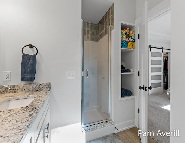 bathroom featuring hardwood / wood-style flooring, vanity, and a shower with shower door