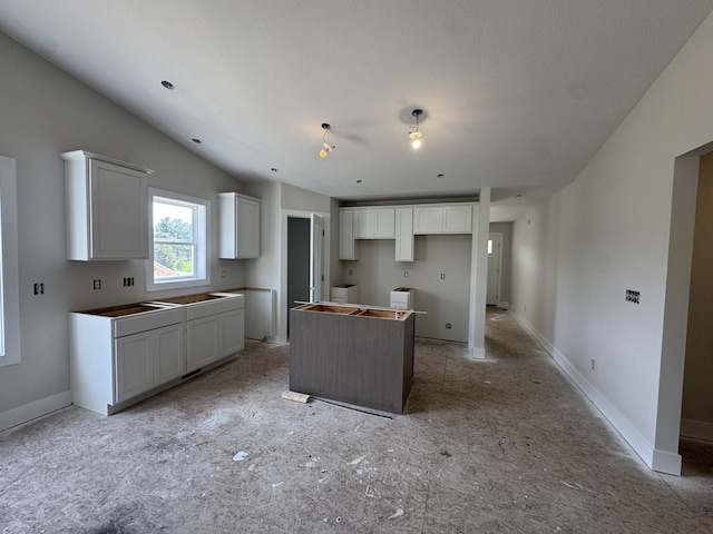 275 Hickory Valley Dr, Kalamazoo, MI 49009 - kitchen featuring a center island, white cabinetry, baseboards, and vaulted ceiling