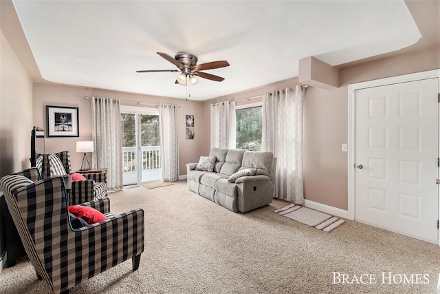 living room featuring a healthy amount of sunlight, ceiling fan, baseboards, and carpet flooring