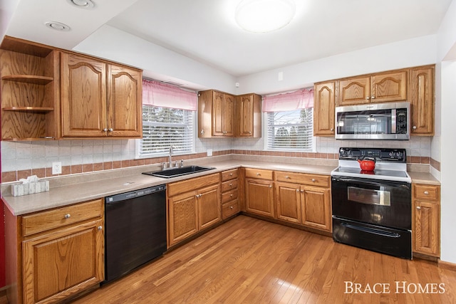 kitchen with a healthy amount of sunlight, black appliances, light wood-type flooring, and a sink