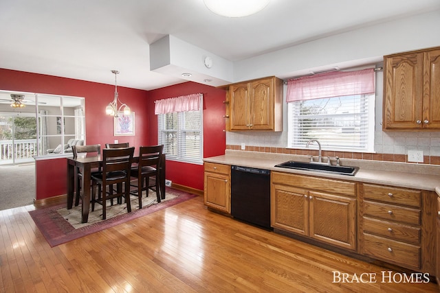 kitchen with light wood finished floors, black dishwasher, brown cabinets, and a sink