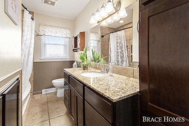 full bathroom with toilet, a wainscoted wall, visible vents, and tile patterned floors