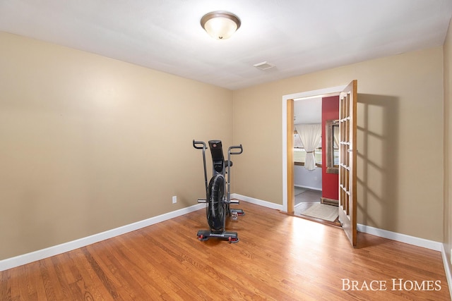 workout area featuring wood finished floors, visible vents, and baseboards