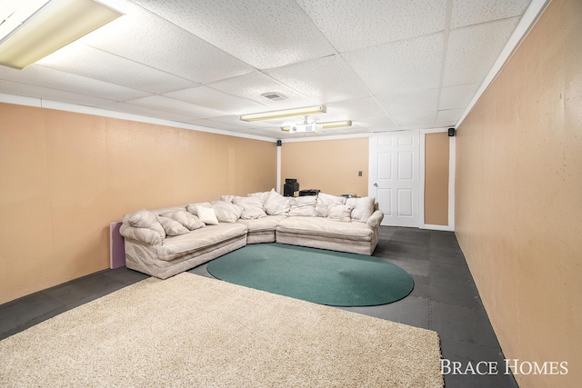 living room featuring concrete flooring, a drop ceiling, and visible vents