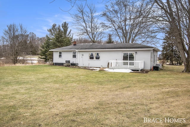 back of house with a chimney, central AC unit, a deck, and a yard