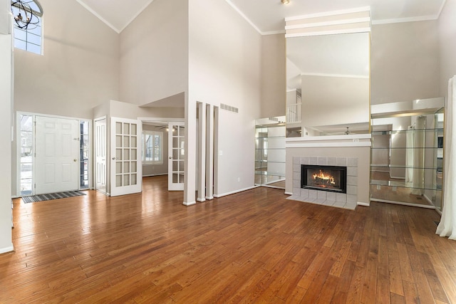 unfurnished living room with lofted ceiling, crown molding, a fireplace, and hardwood / wood-style flooring