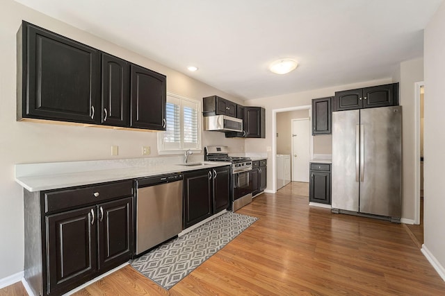 kitchen featuring sink, light hardwood / wood-style flooring, stainless steel appliances, independent washer and dryer, and extractor fan