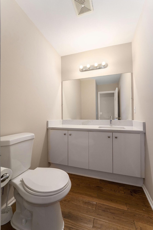 bathroom with hardwood / wood-style flooring, vanity, and toilet