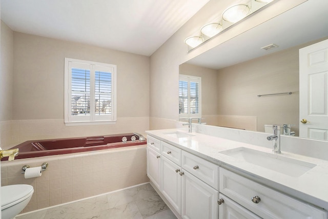 bathroom with vanity, a relaxing tiled tub, and toilet